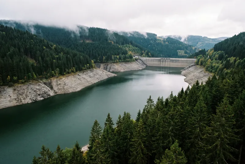 Talsperre im Schwarzwald bei niedrigem Wasserstand, dunkles Wasser zwischen steilen Fichtenhängen