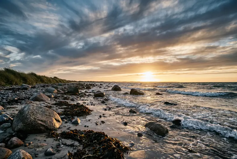 Steiniger Ostseestrand im Morgenlicht mit auslaufenden Wellen